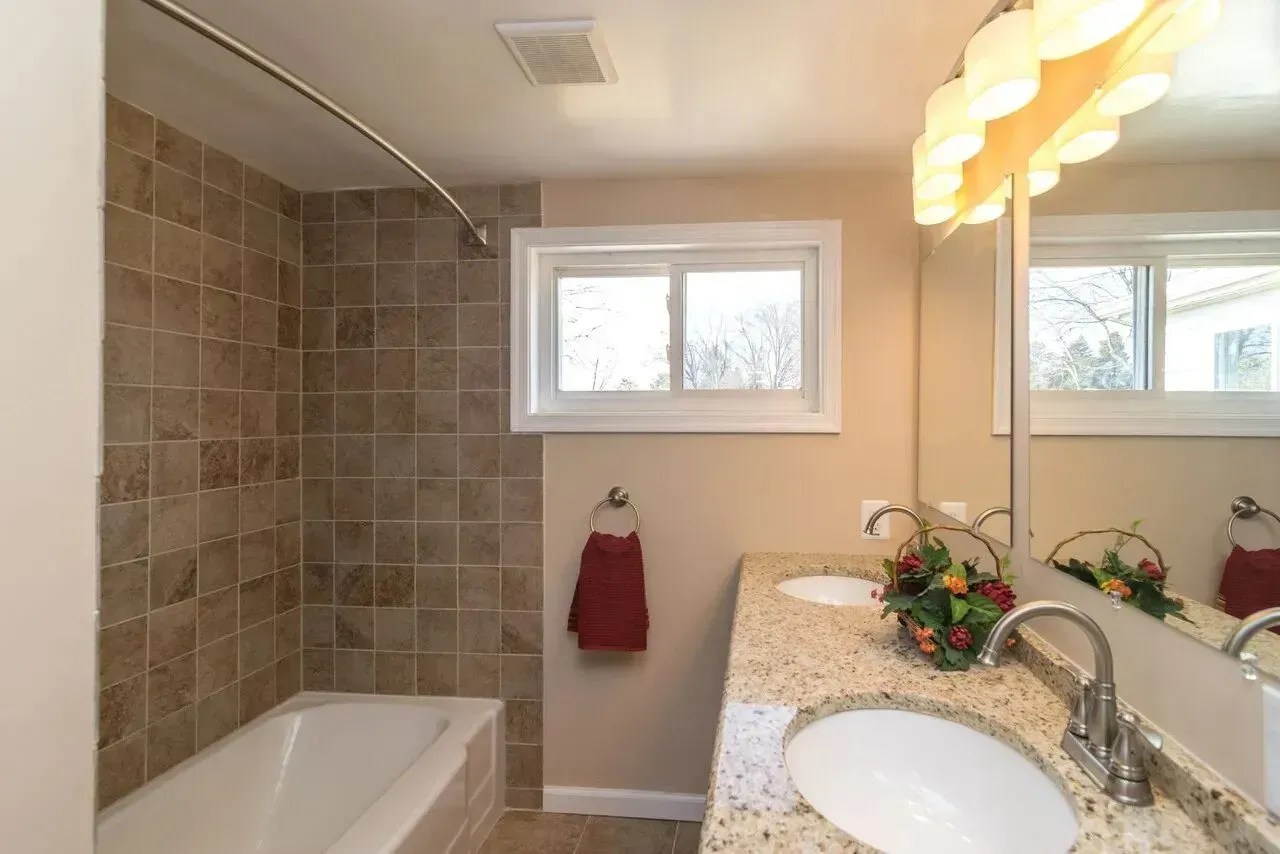 A bathroom with a tub , sink and mirror