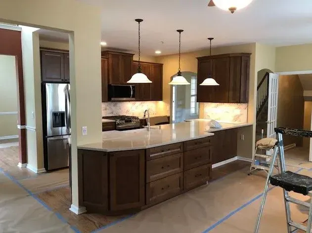 A kitchen with wooden cabinets and stainless steel appliances is being painted.