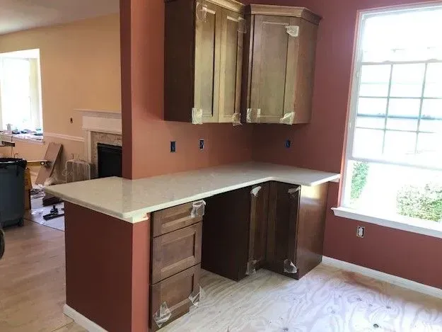 A kitchen under construction with wooden cabinets and a white counter top.