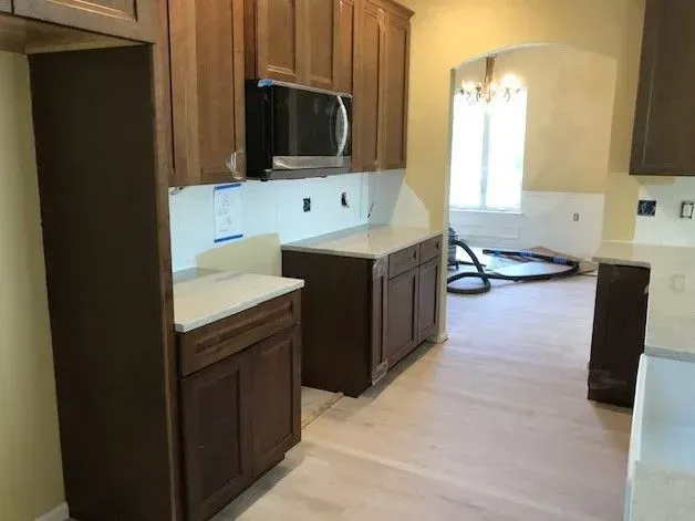 A kitchen with wooden cabinets , granite counter tops , and a microwave.