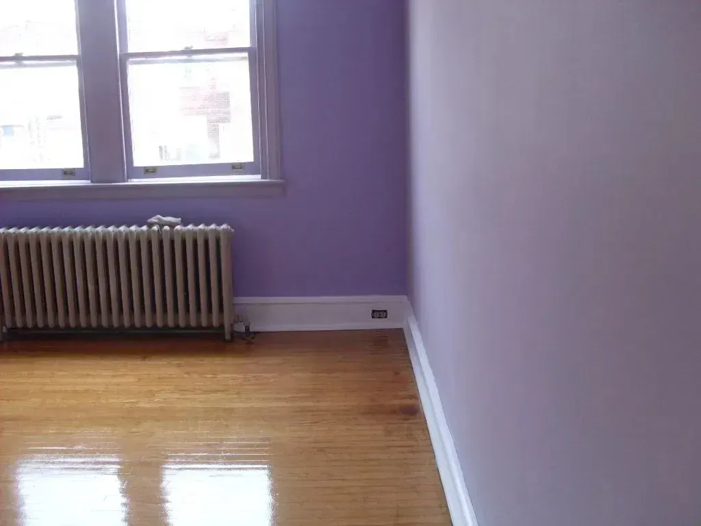 An empty room with purple walls and a radiator.