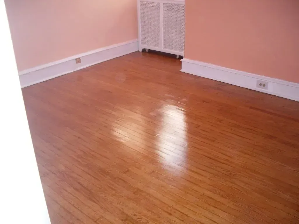 An empty room with hardwood floors and pink walls.