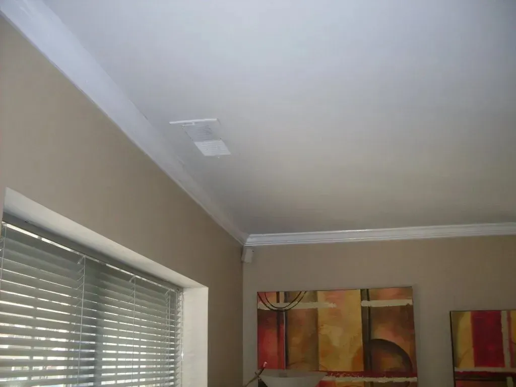 A room with a painting on the wall and blinds on the windows