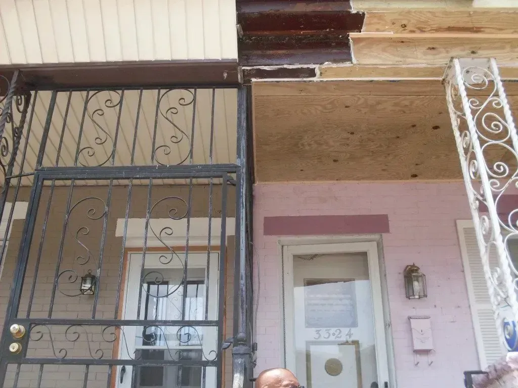 A man is standing in front of a house with a wrought iron gate