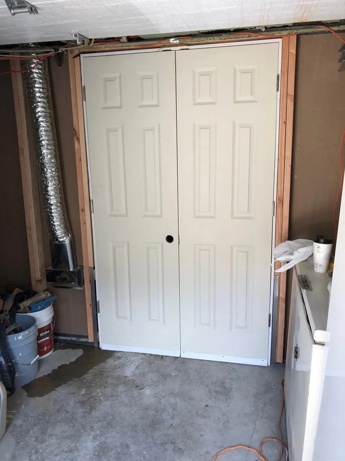 A white door is sitting in a room next to a refrigerator.