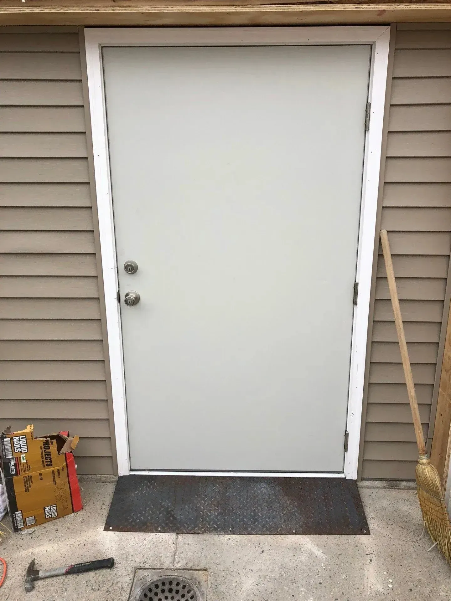 A white door is sitting on the side of a building.