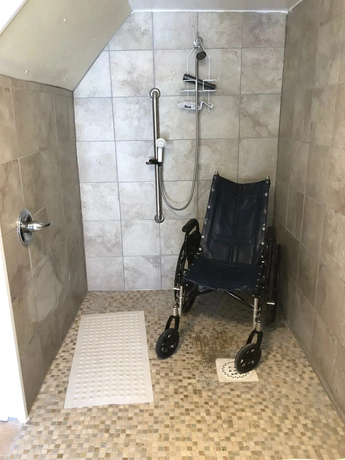 A wheelchair is sitting in a walk in shower.