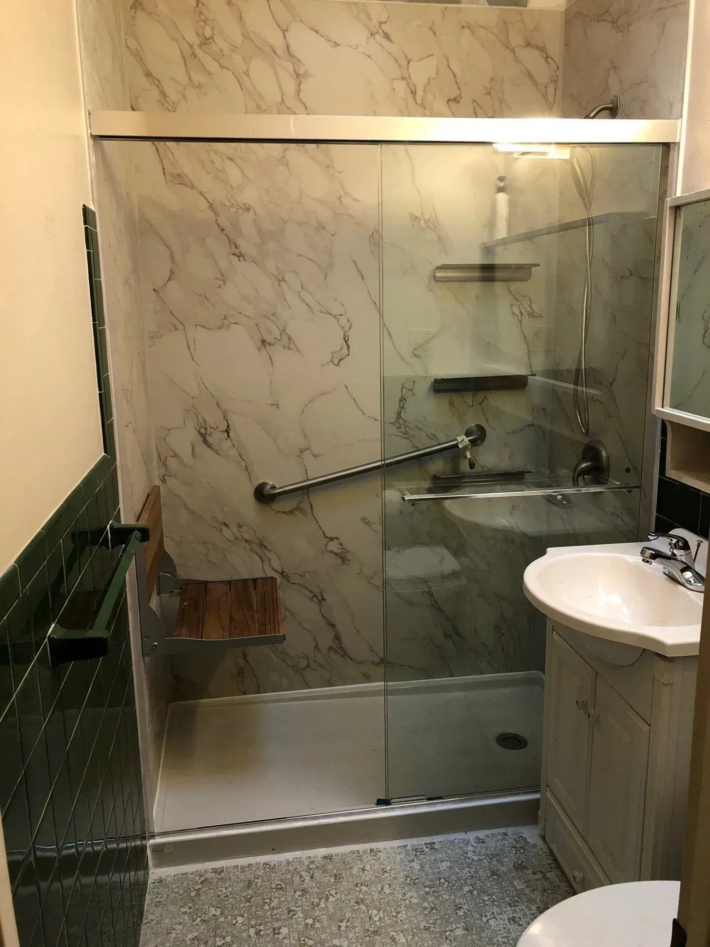 A bathroom with a walk in shower , sink and toilet.