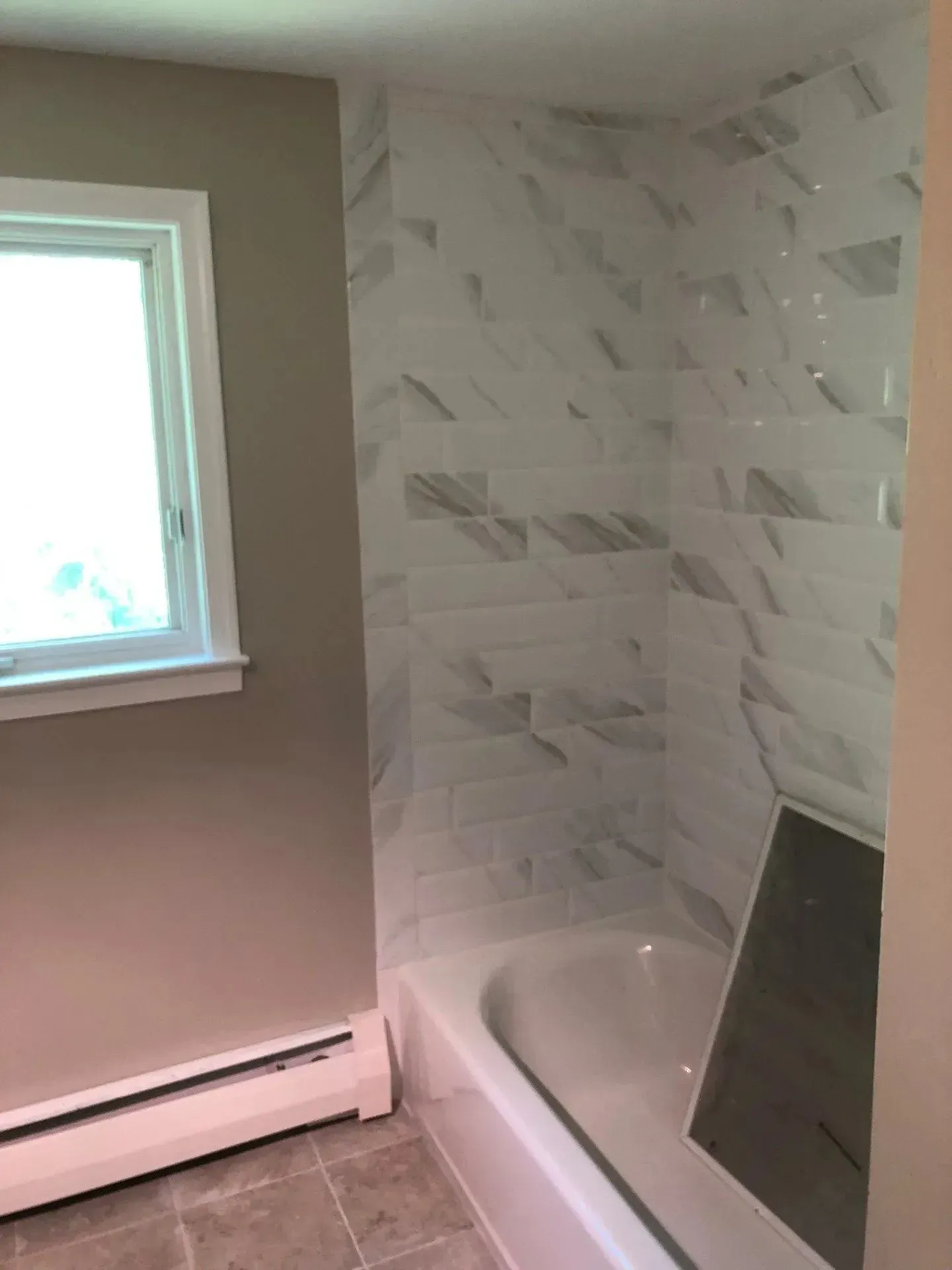 A bathroom with a bathtub and a window.