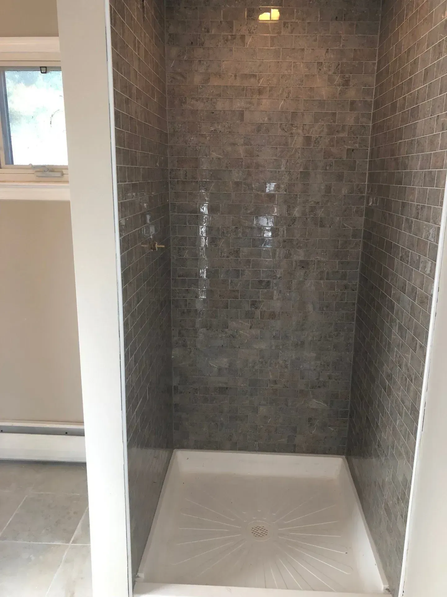 A bathroom with a walk in shower and a window.