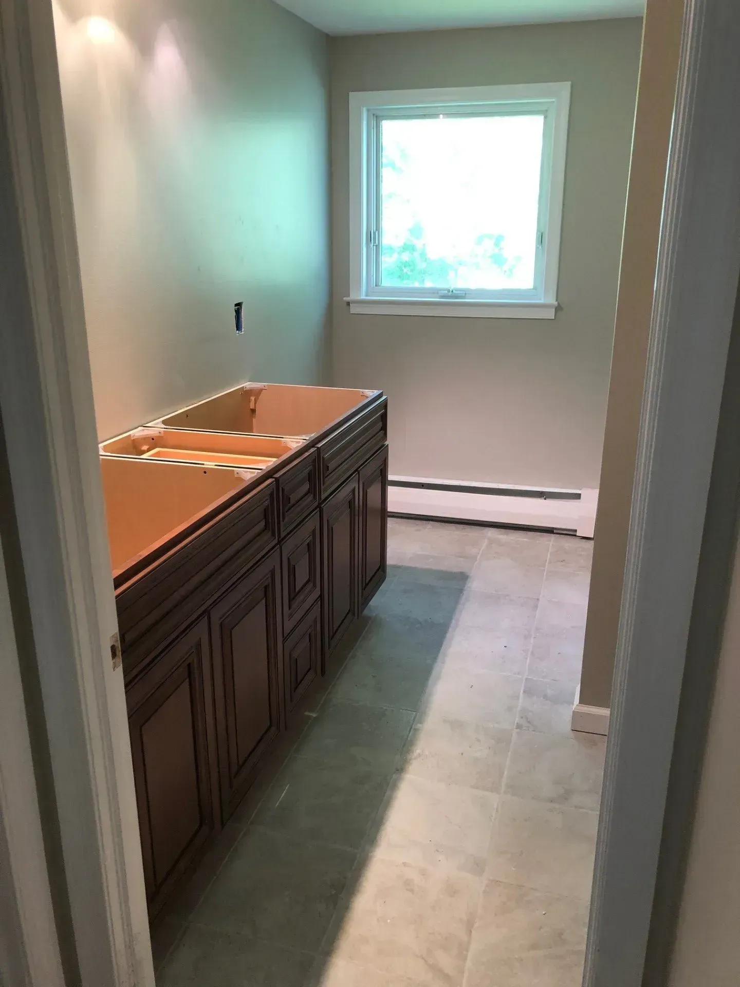 A bathroom with a sink , cabinets and a window.