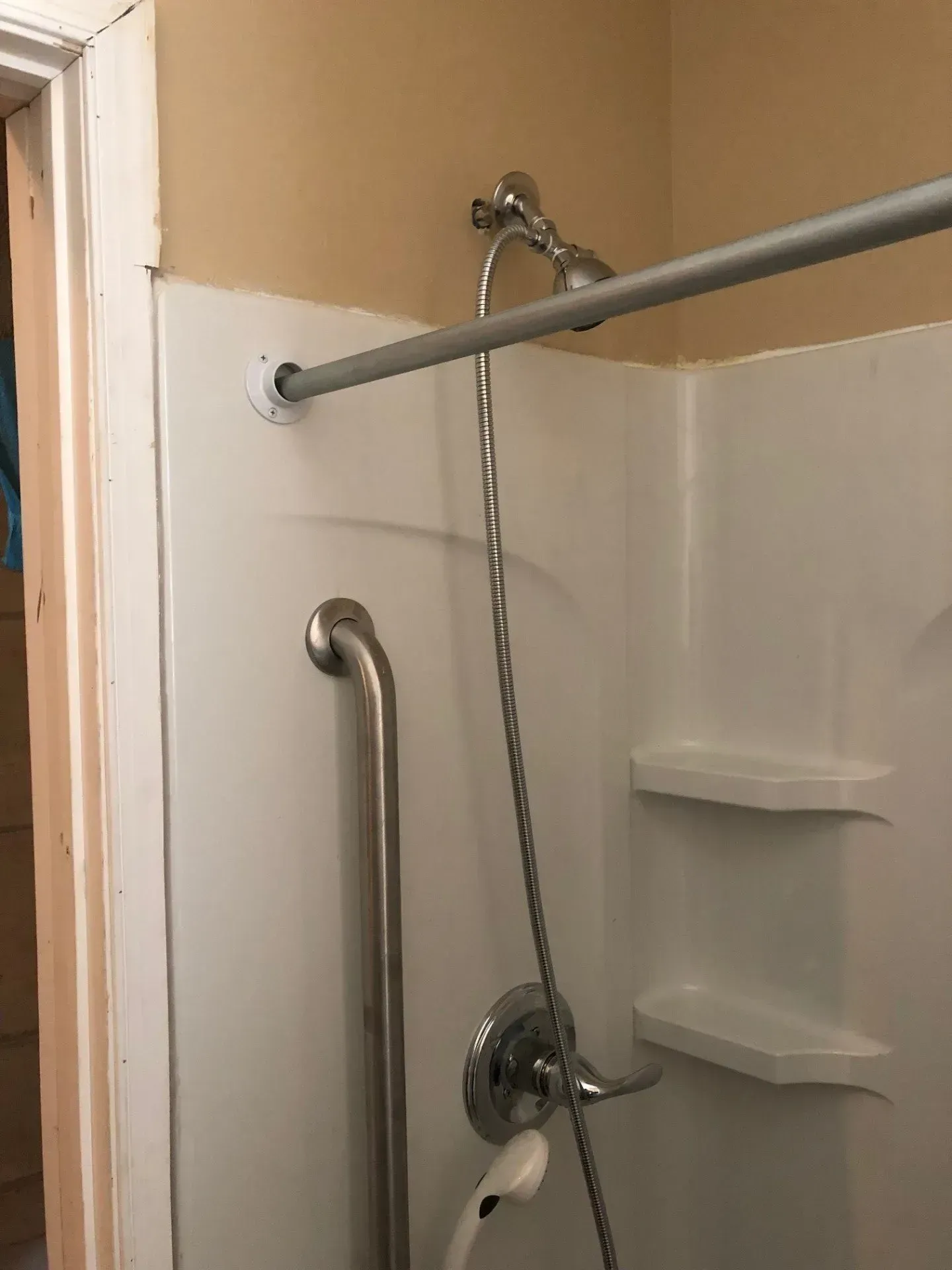A shower with a hand rail and a shower head.