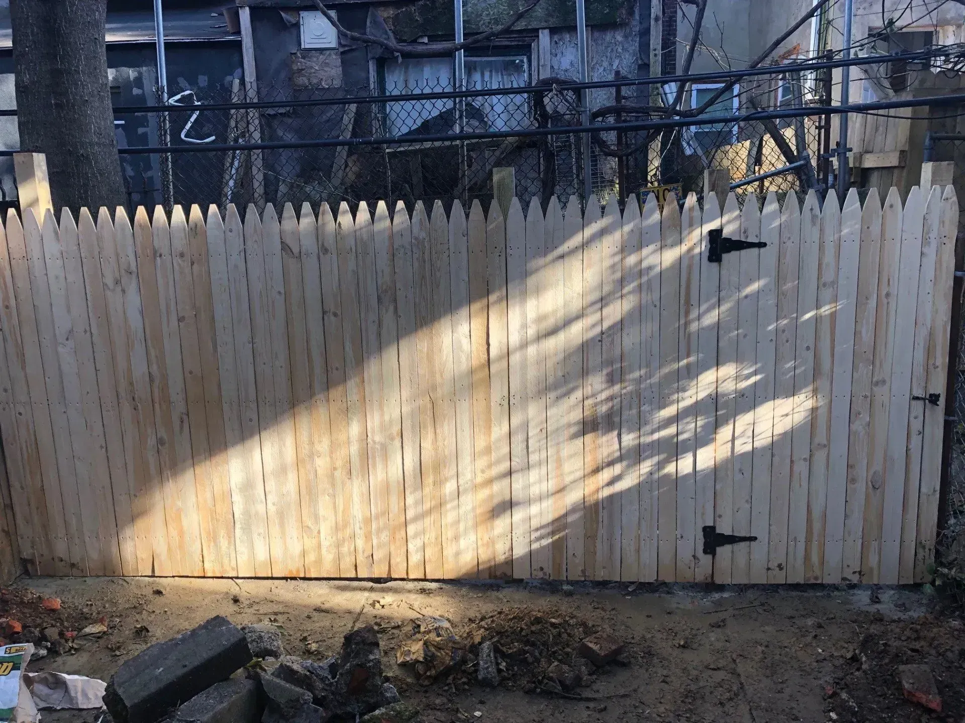 A wooden fence with a gate is being built in a backyard.