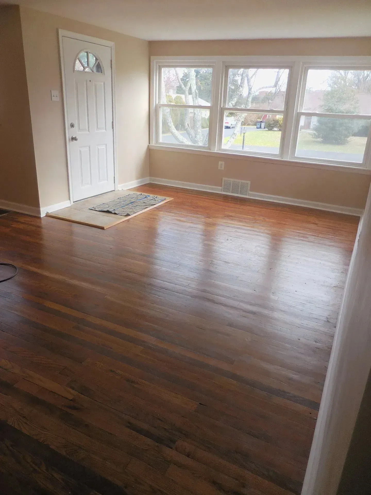 An empty living room with hardwood floors and a door.