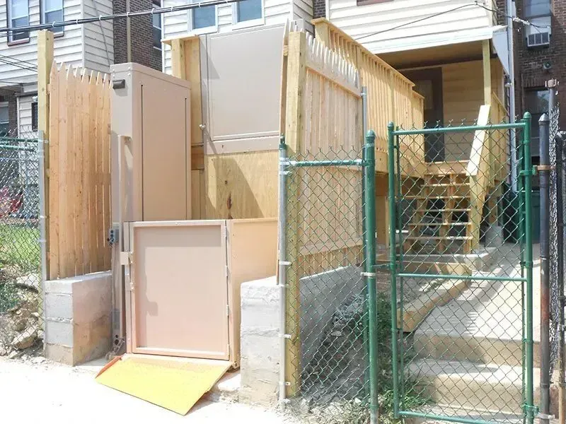 A building with a ramp and stairs behind a chain link fence.