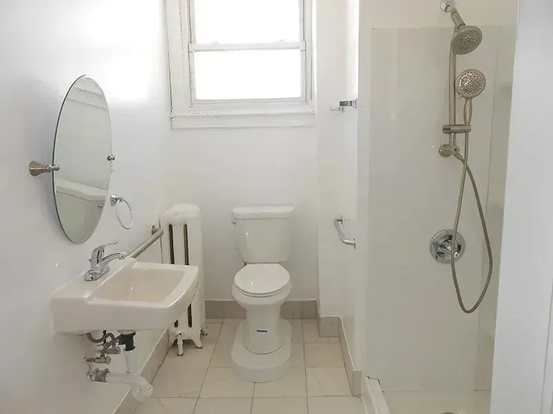 A bathroom with a toilet , sink and shower.