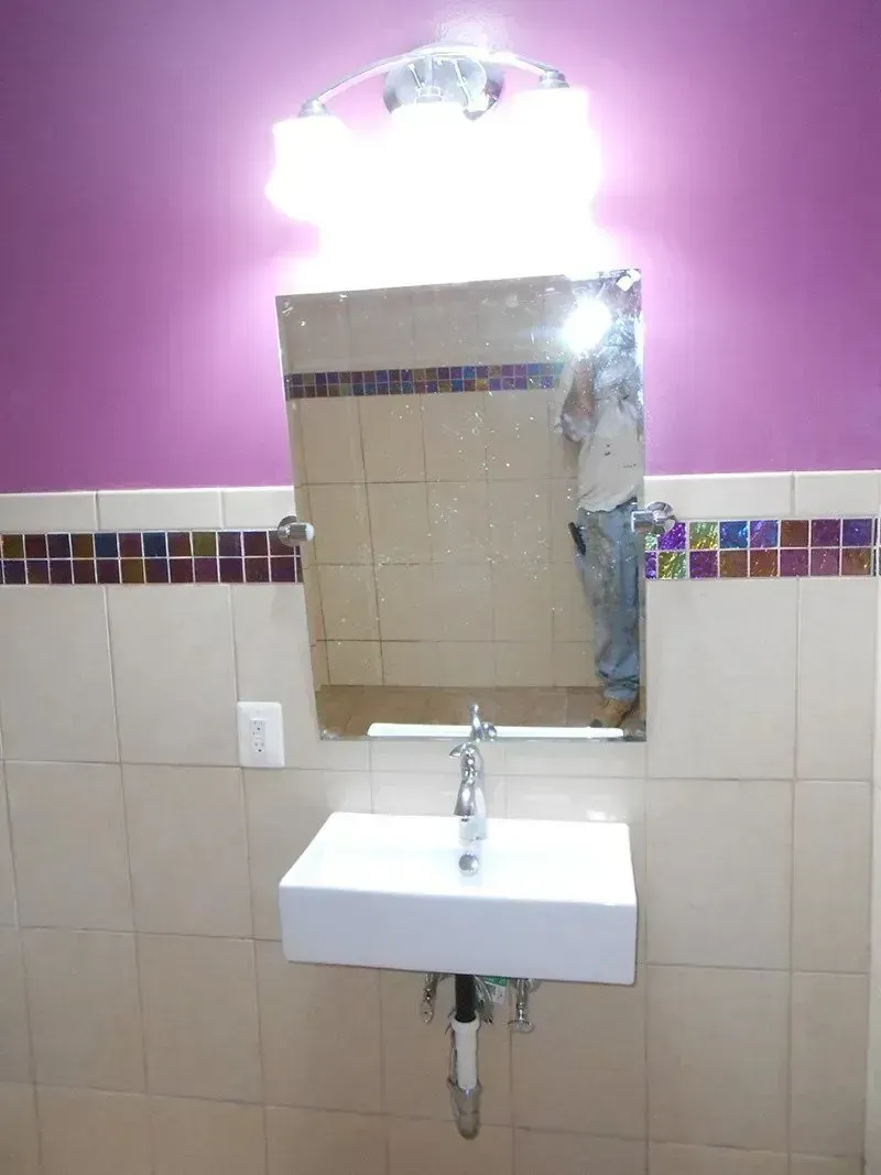 A bathroom with purple walls and a sink and mirror