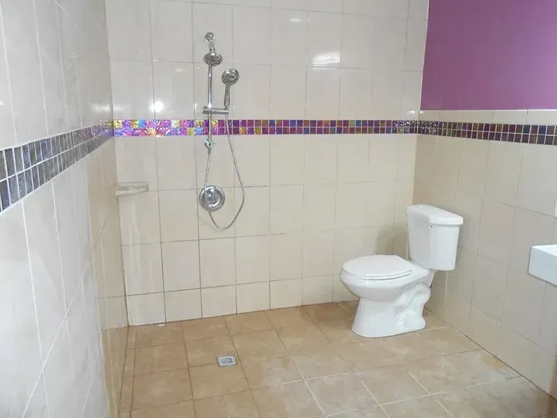 A bathroom with a toilet , shower and sink.