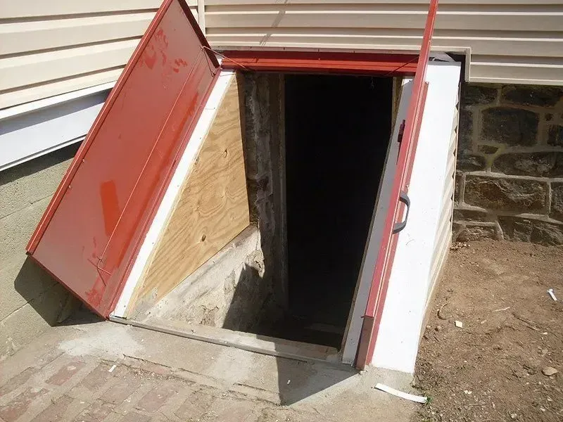 A red door is open to a basement door