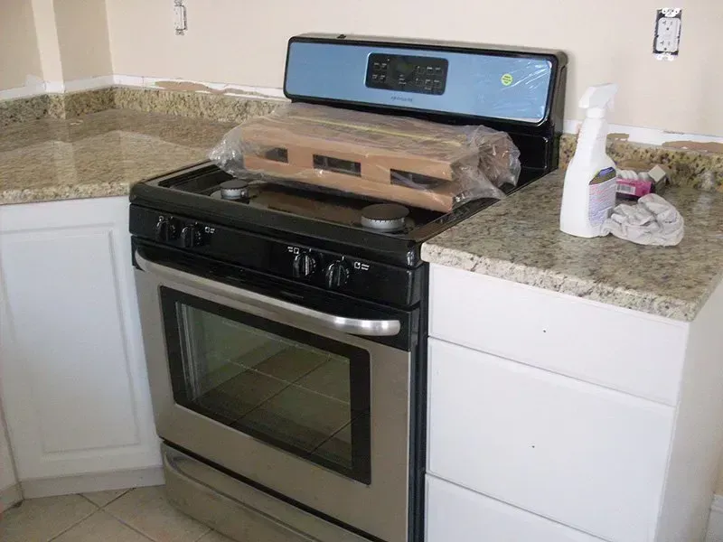A kitchen with a stove top oven and a spray bottle on the counter