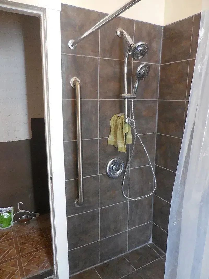 A bathroom with a shower and a towel on the wall