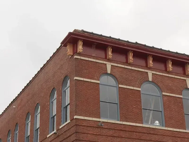 A brick building with arched windows and a red roof
