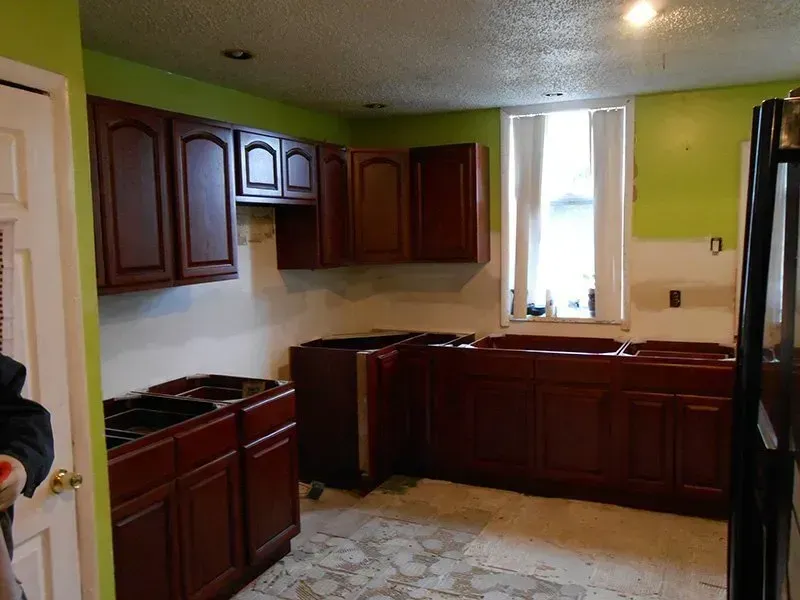 A kitchen with wooden cabinets and green walls
