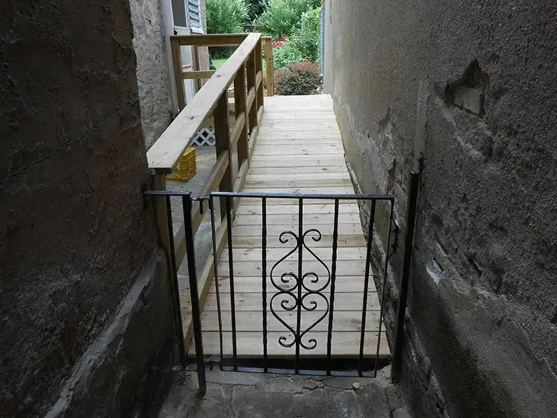 A wooden ramp with a wrought iron gate leading to it