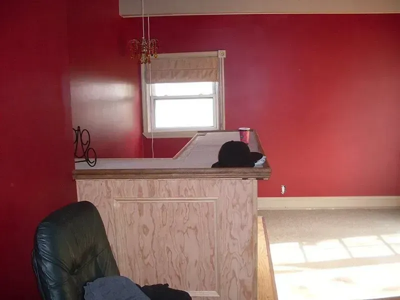 An empty room with red walls and a chair