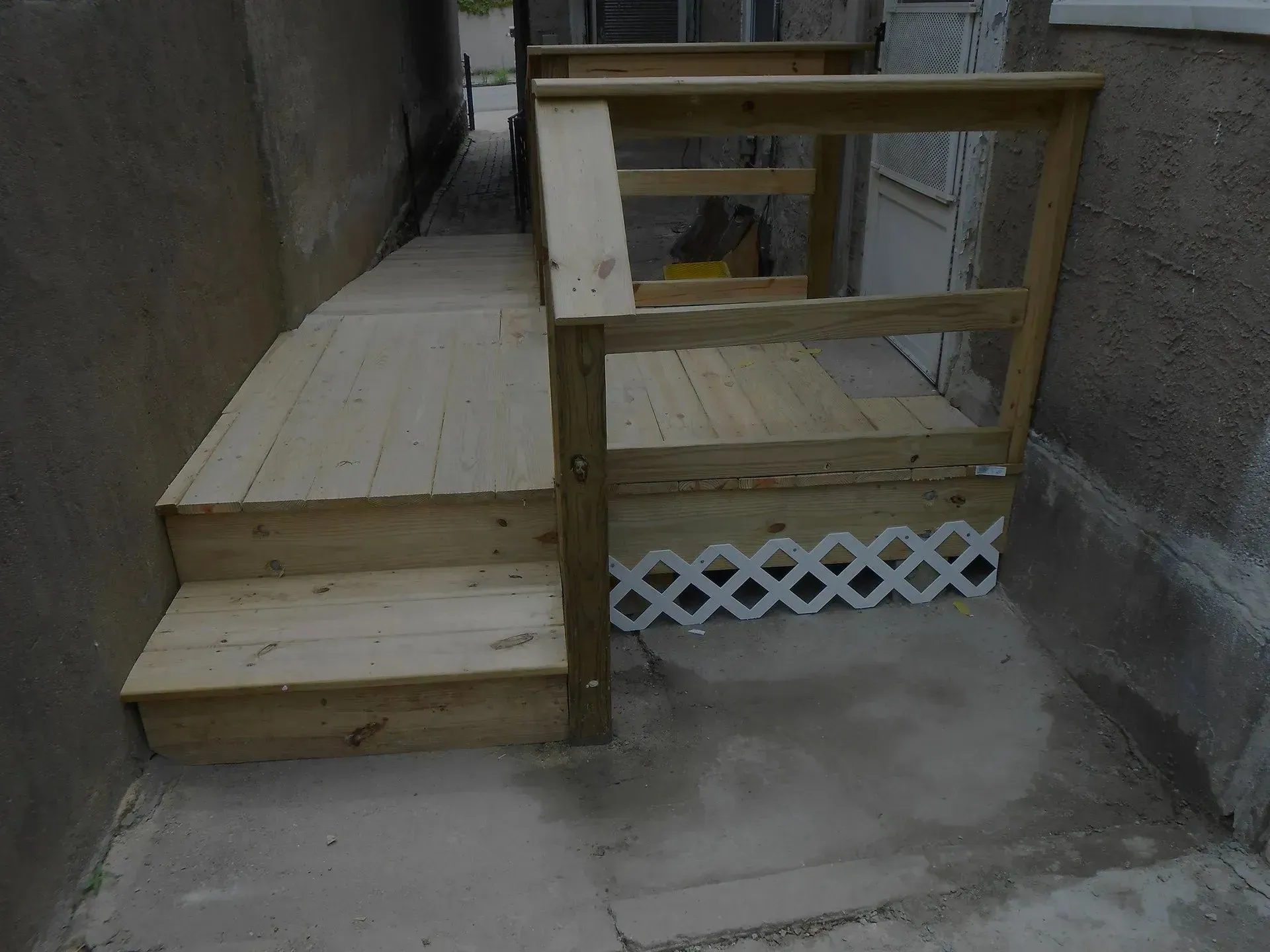A wooden deck with stairs and a railing on the side of a building