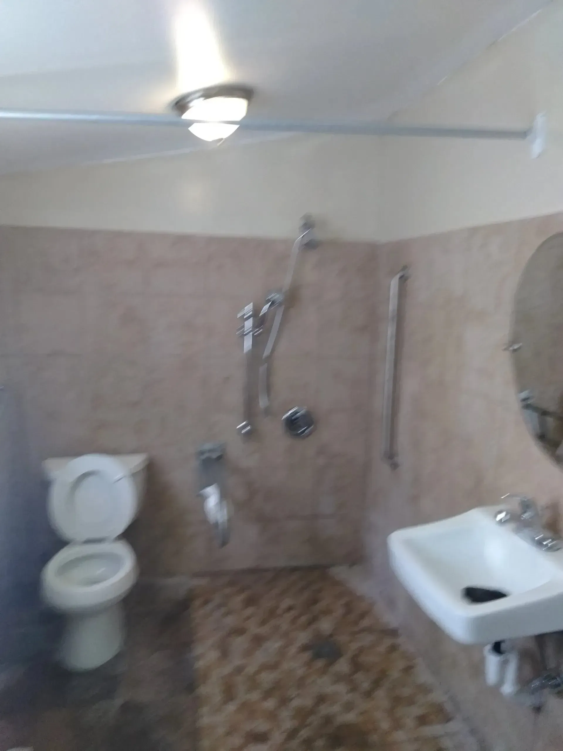 A bathroom with a toilet , sink , shower and mirror.