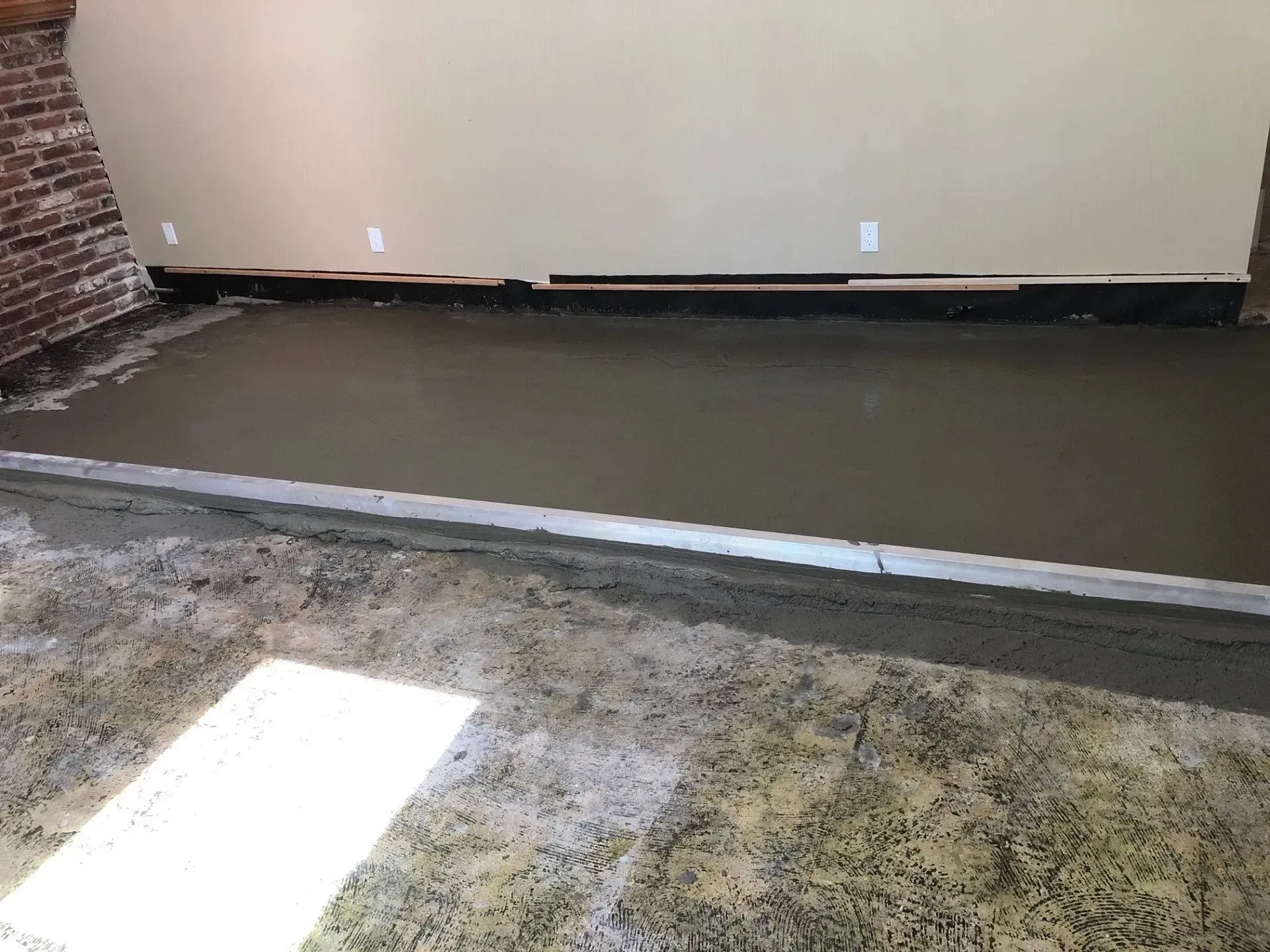 A room with a concrete floor and a brick wall.