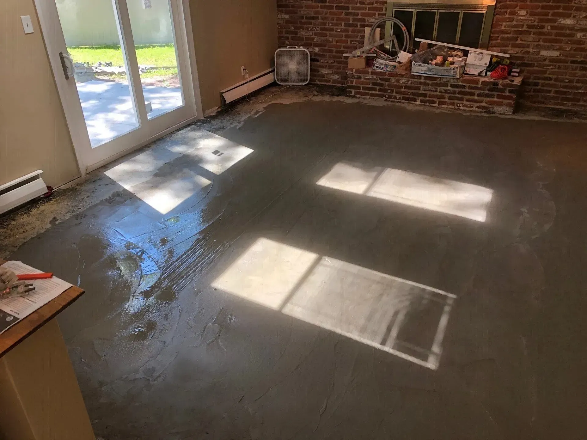 A living room with a concrete floor and a brick wall.