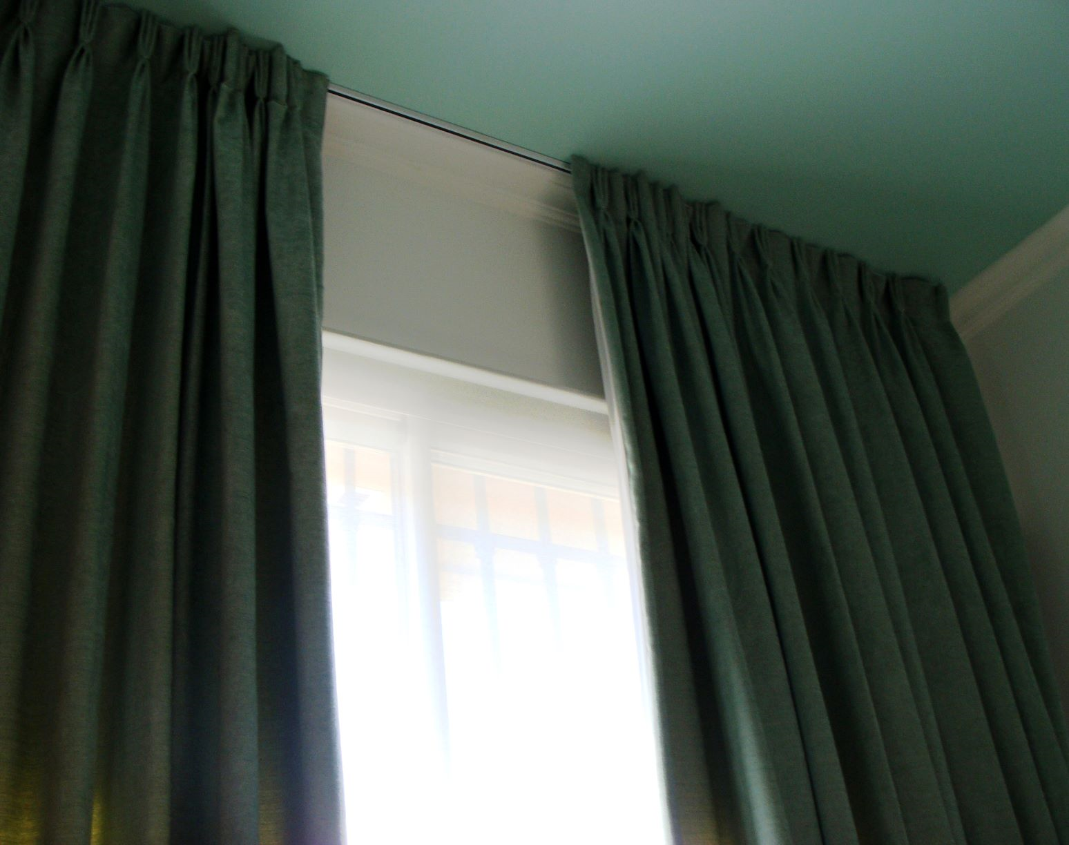 Riel de cortina blanco con deslizadores espaciados uniformemente para colgar cortinas.