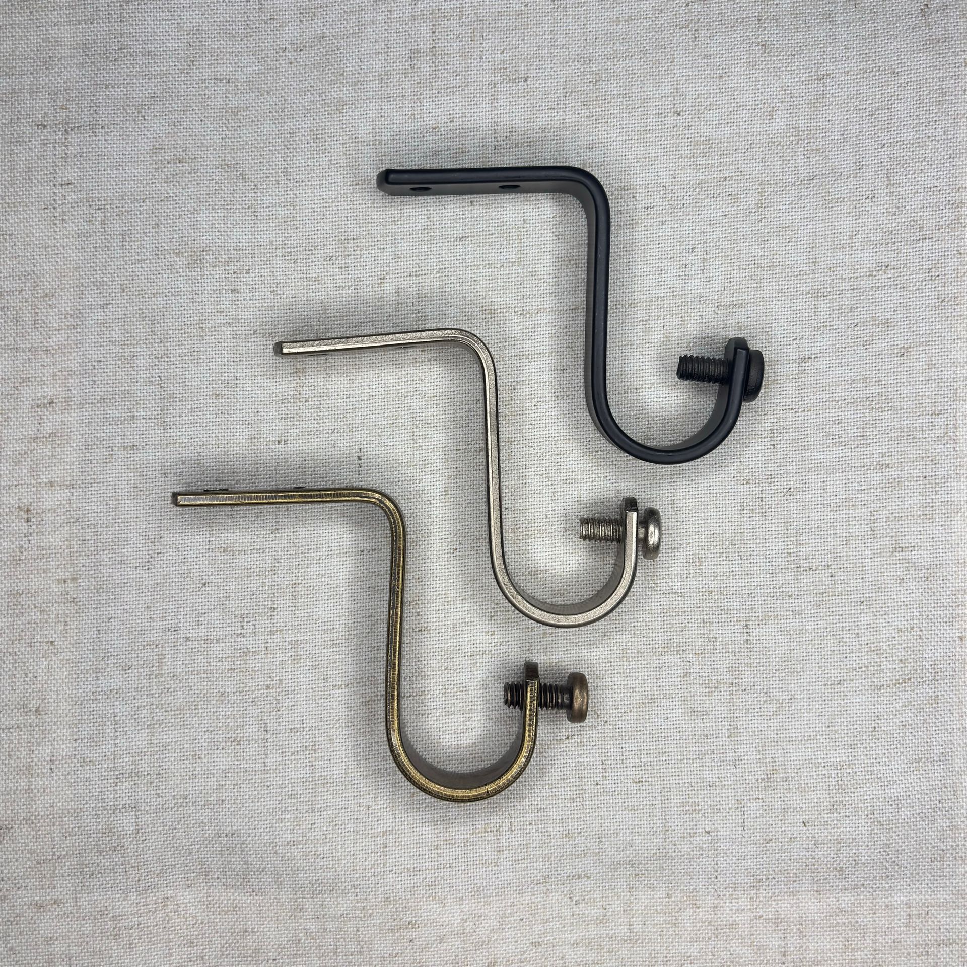 Soporte de barra de cortina negro con tornillos y anclajes de pared sobre una superficie texturizada.