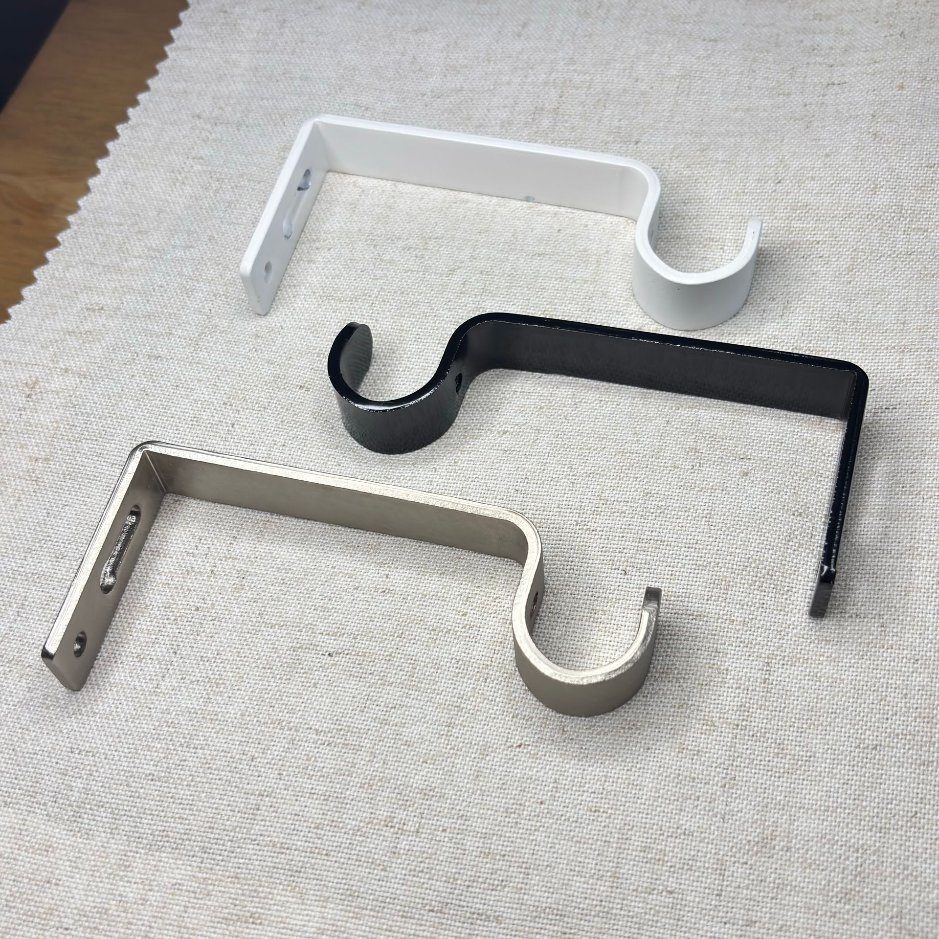 Soporte de barra de cortina cromado con tornillos y anclaje de pared sobre superficie texturizada.