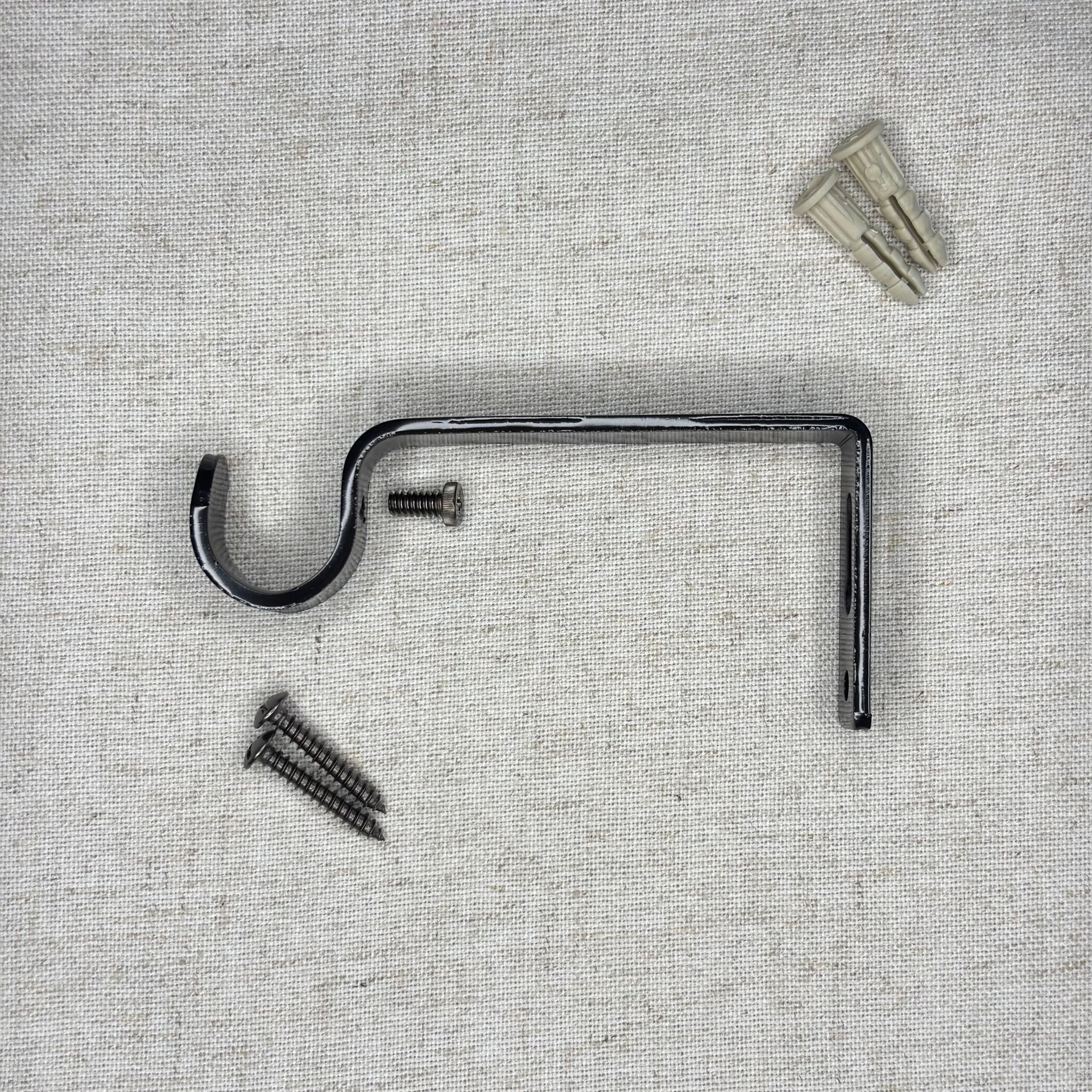 Soporte de barra de cortina cromado con tornillos y anclaje de pared sobre superficie texturizada.