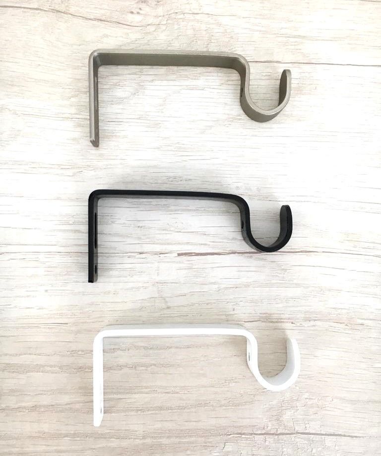 Tres ganchos de metal están colocados encima de una mesa de madera.