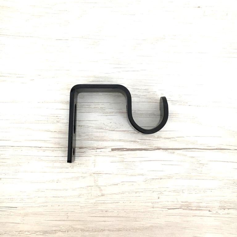 Un gancho de metal negro está sobre una mesa de madera.