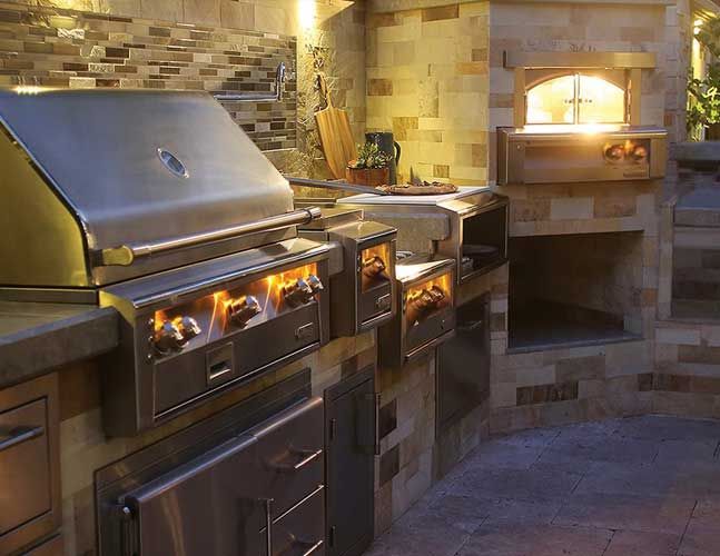 An outdoor kitchen with a grill and a pizza oven