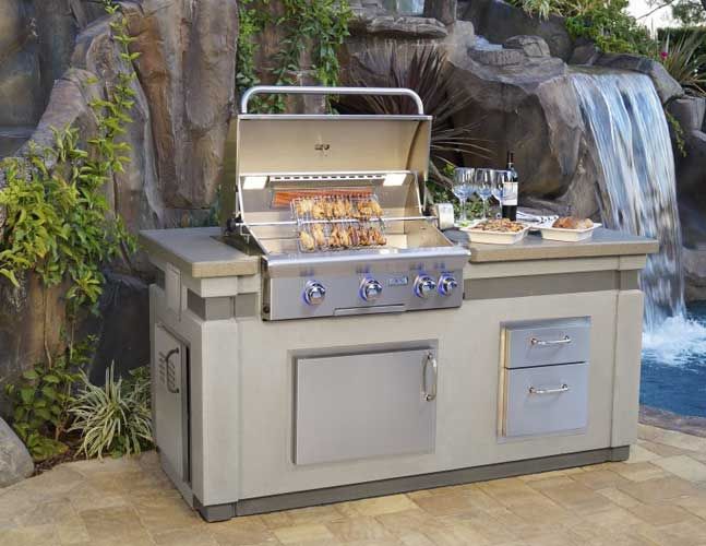 A stainless steel grill is sitting in front of a waterfall.