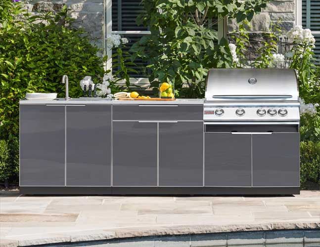 An outdoor kitchen with a grill and sink next to a pool.