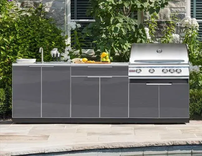 An outdoor kitchen with a grill and sink next to a pool.