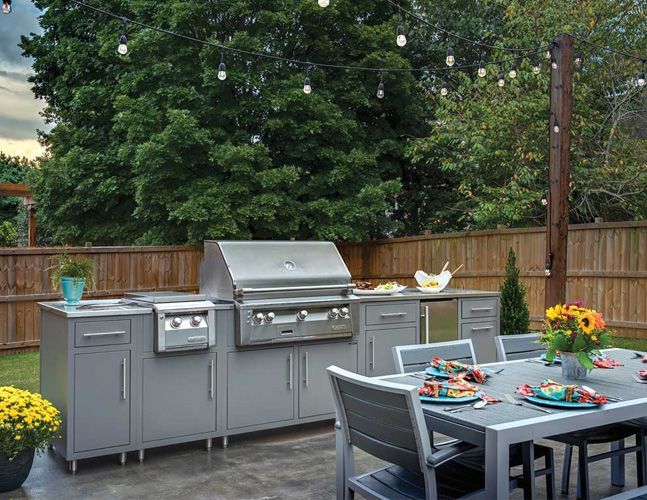 A patio with a table and chairs and a grill.