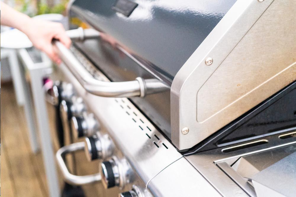 A person is opening the lid of a stainless steel grill.