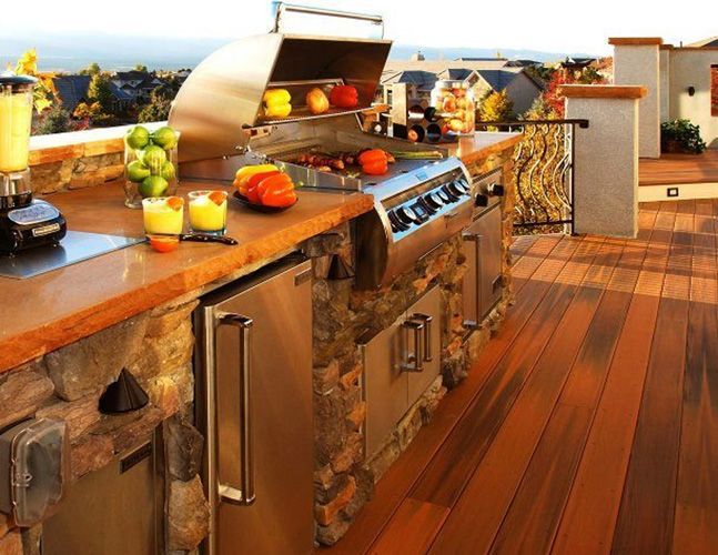 An outdoor kitchen with a grill and fruit on the counter