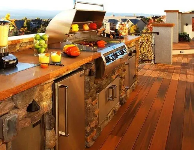 An outdoor kitchen with a grill and fruit on the counter