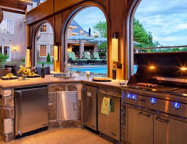 A kitchen with a grill and a swimming pool in the background