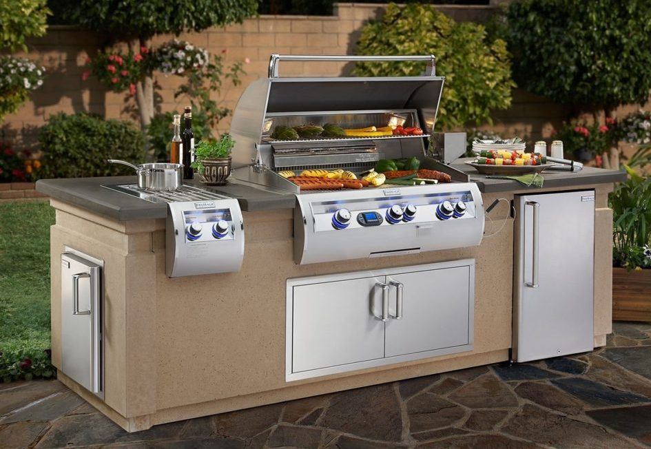 An outdoor kitchen with a grill and a refrigerator