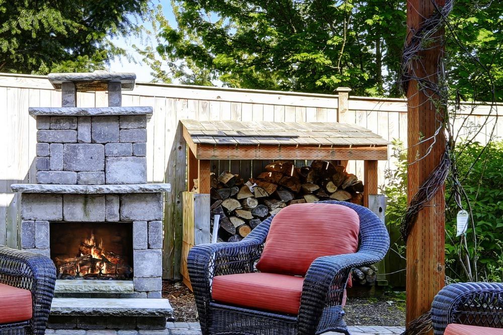 A patio with wicker chairs and a fireplace.